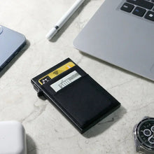 Load image into Gallery viewer, Black cardholder with cards on a light gray surface with a laptop and watch.