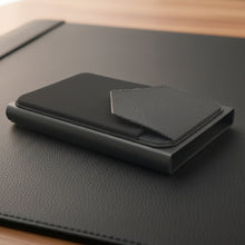Load image into Gallery viewer, Black Ozerlo Men_Women_Luxury_Wallet on a wooden surface with blurred lights in the background